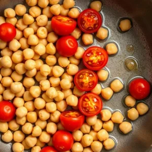 Chickpeas and tomatoes sautéing in olive oil in a skillet